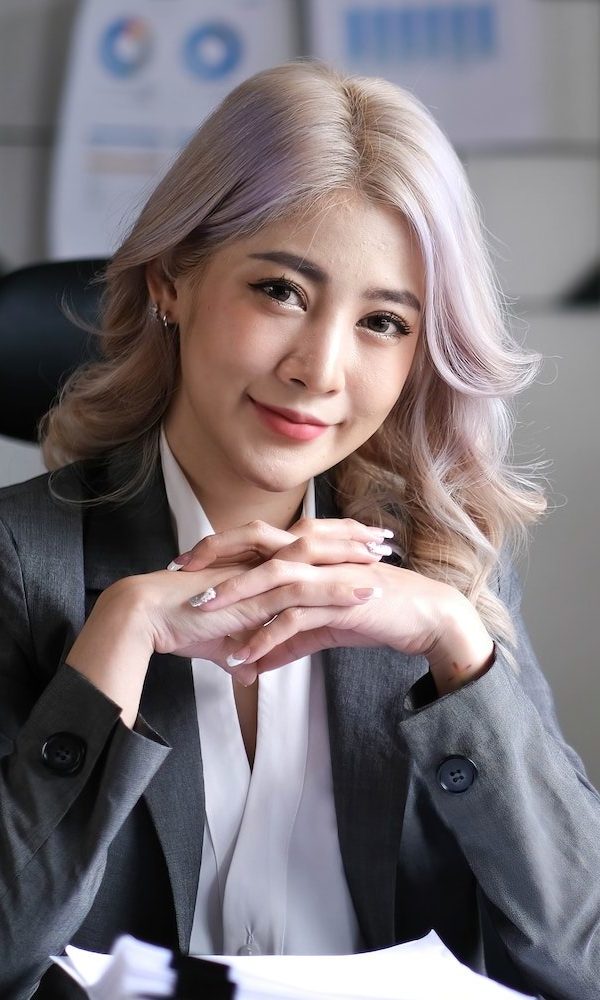 charming-asian-woman-working-at-the-office-using-a-laptop-looking-at-the-camera--e1683099616489.jpg